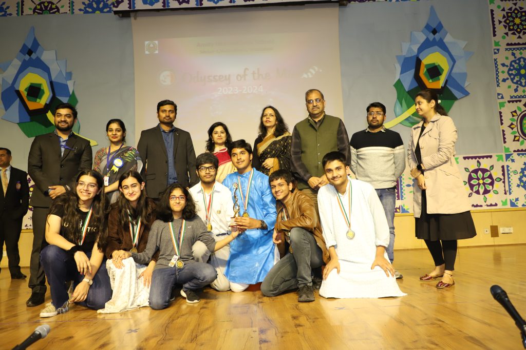 Award-winning student team celebrating success on stage with mentors and medals
