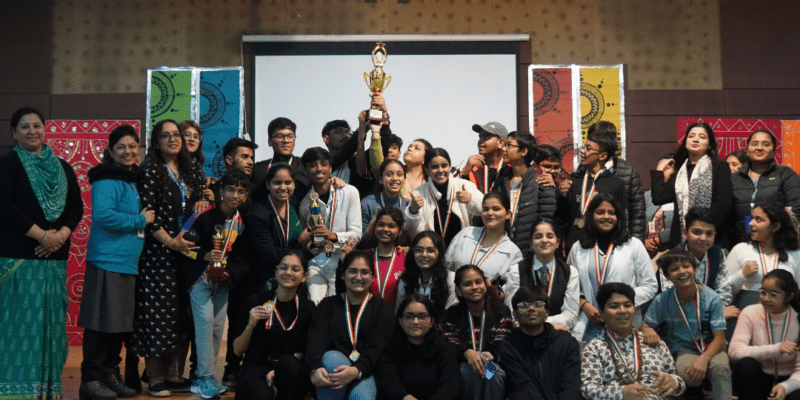 Award-winning student team celebrating success on stage with mentors and medals